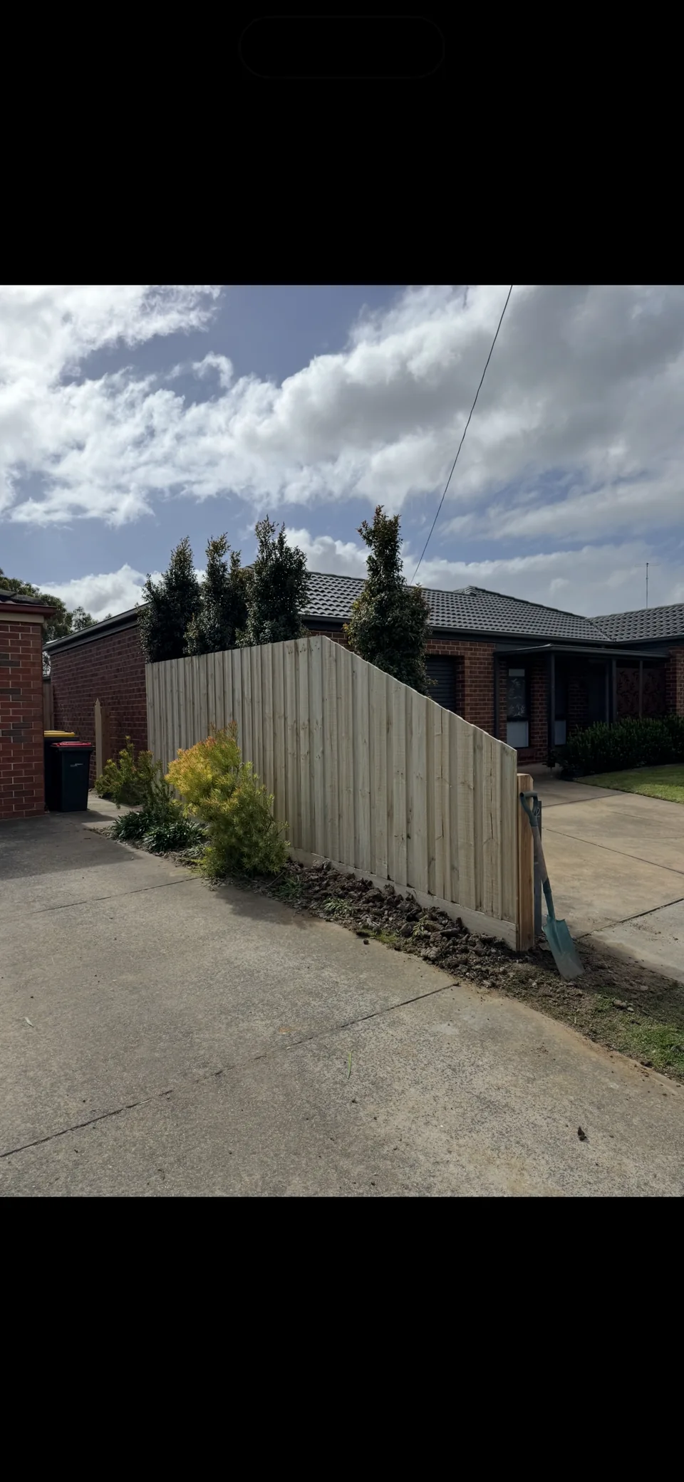 1.95 m timber paling fence with a sloping top between two driveways